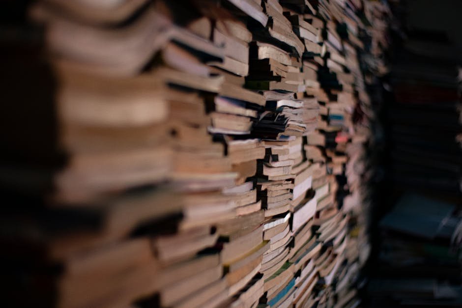 Stack of well-worn paperback books on a wooden table beside a mug of tea